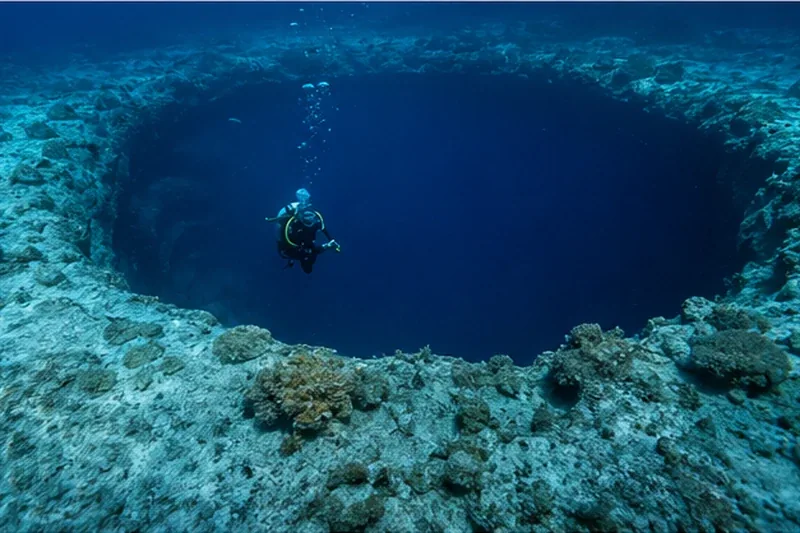 Bahamas blue hole dive site with deep circular opening in clear blue water