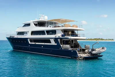 A liveaboard dive boat at anchor on clear tropical water