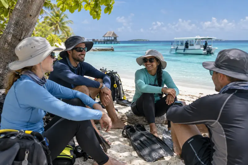 Divers wearing rashguards and sun hats in shade during strong midday sun in the Maldives